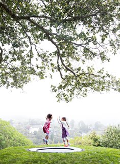 A series of mounded earth forms offers an enticing topography for play, including one that holds an in-ground trampoline. 