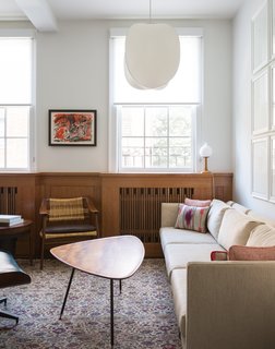 725 Square Feet and Loads of Modern Gems - Photo 1 of 6 - "Our love for Japanese design, and respect for it as a precursor to the midcentury aesthetic, came into the design of the radiator covers," architect and designer Suchi Reddy says. In the living room, a sofa by esteemed midcentury designer Milo Baughman joins a Bambi lounge chair by Norwegian designers Rolf Rastad and Adolf Relling. The pendant light is the Mori Leaf model from Rich Brilliant Willing. Architect Matthew Viederman designed new finishes for the floors, bathrooms, and kitchen. Reddy's team spearheaded the furniture selection as well as the millwork at the radiators.