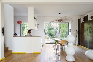 In the living area, a 2010 Vertigo lamp by Constance Guisset hangs above a 1974 Gijs Bakker Strip table; the residents believe the floor lamp in the foreground is Murano glass. Dark panels of metal, left behind by the previous homeowners, were stored outside until a rich patina developed. Now they hide a library.