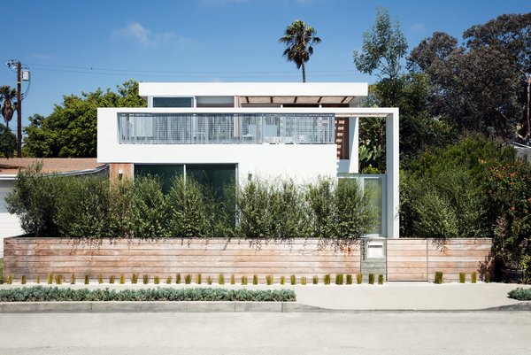 Amid a Hotbed of Architecture, This Home Holds Its Own - Photo 3 of 9 - His wife, landscape designer Kathleen Ferguson, planted evergreen shrubs out front, lending the property additional privacy. Located on the new upper floor, the master bedroom features sliding glass doors that open to a spacious outdoor terrace. The bed frame and side table are from Diva Furniture; the felt pendant is from YLighting. 