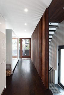 A grille of walnut slats, designed by Syme and made by the local millworkers MCM, delineates the edge of a new stair with open treads made of hot-rolled steel. Tall Bulthaup cabinets mark the edge of the dining area; Evans, a mechanical engineer, had them custom-made to conceal heating ducts that vent almost invisibly through the top edge. 