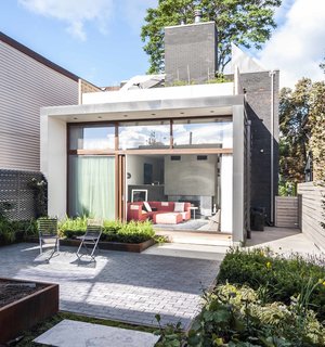 In the rear of the house, a new addition extends the living space and adds a roof terrace off the second-floor master bedroom. A garden is accessible through a wall of sliding glass doors with Sapele mahogany frames, set back to control solar gain. 