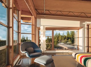 An Eero Saarinen Womb chair and ottoman, an Isamu Noguchi Akari lamp, and forest views make for a cozy reading nook. 