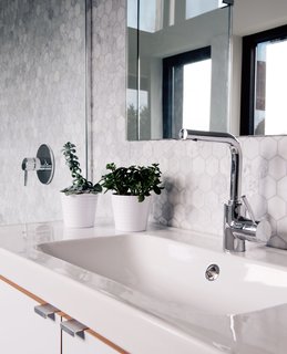 In the master bathroom, an IKEA sink sits in a cabinet fabricated by Abodian. Tiffany found the marble tiles online; the faucet is by Grohe. 