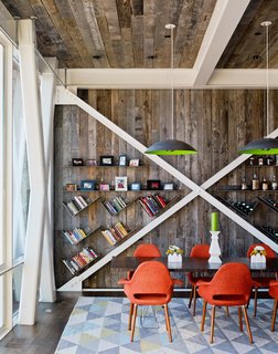 High Above Traditional Charleston, a Modern Home Finds its Roost - Photo 2 of 7 - The interior nods to its host structure’s heritage with some walls and the ceiling clad in reclaimed oak from a Kentucky farmhouse. Custom pendants by Mickus Projects hang above a Curzon table from Modloft.