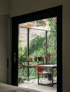 This Los Angeles Home is Driven by Automotive Design - Photo 3 of 9 - Continuing the material palette, the back patio is furnished with a custom granite-and-steel table and vintage Eames fiberglass chairs.
