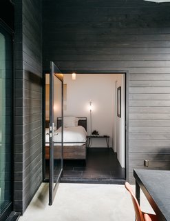 This Los Angeles Home is Driven by Automotive Design - Photo 4 of 9 - The patio is accessed from the master bedroom via a large pivot door. The bed and mirror are from Crate and Barrel; the pendant is from Droog. The couple made the wall sconces themselves.