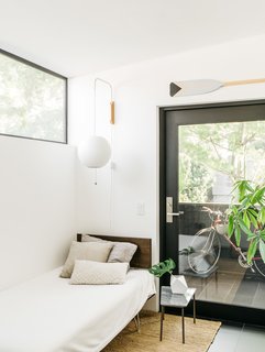 This Los Angeles Home is Driven by Automotive Design - Photo 9 of 9 - The loft is furnished with a Modernica rocking chair and custom casework by Dan Taron. A Case Study bed and Nelson ball lamp make for a cozy nook in the guest room, which has a private outdoor patio. White walls and black steel window frames serve to accentuate the home’s unique geometry.