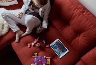 Automation Eliminates Tedious Chores for Dallas Homeowners - Photo 4 of 6 - The Thomases’ daughter lounges in the living room on a sofa from Mitchell Gold + Bob Williams.