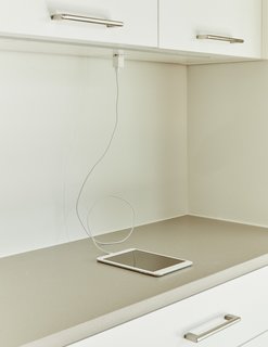 Automation Eliminates Tedious Chores for Dallas Homeowners - Photo 6 of 6 - In the dining room, a Brendan Ravenhill fixture hangs above a custom walnut table and Wishbone chairs by Hans Wegner. Customized features, like an outlet flush-installed beneath the kitchen cupboards, subtly conceal signs of a wired house. 