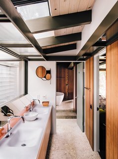 Fung + Blatt designed the master bathroom vanity, which features Agape washbasins and fixtures and an angled mirror that reflects the oak trees seen through the skylights. 
