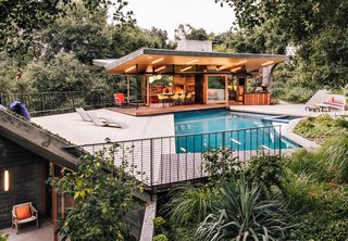 Rising from the edge of the pool deck, a planted overhang shelters a gym and sauna below.