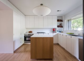 American Beauty - Photo 4 of 8 - <span style="line-height: 1.8;">A 1980s renovation dated the kitchen, </span>so Chris integrated a modern white design with a custom island. The oven is by IKEA; other major appliances were purchased from the Habitat for Humanity ReStore. 