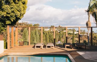<span style="line-height: 1.8;">Contractor Roderick McGrew was tasked with removing the massive A-frame structure that the former owners had added to enclose the rear patio and the pool. "Removing it took three times as long as we thought it would," Tyler recalls. McGrew also redid the deck and installed wood floors throughout the interior. </span>The deck commands panoramic views of the city and the ocean in the distance. The lounge chairs are from IKEA. 