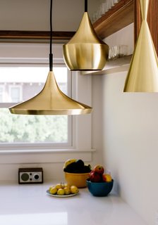 Brass pendants by Tom Dixon hang in the kitchen.