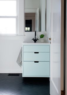 Custom-built cabinetry and matte-black fixtures by Dornbracht make up the revamped guest bathroom, a drastic change from its previous state. 