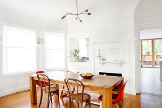 Check Back - Photo 3 of 14 - Three furniture icons, in pairs, surround the dining room table: the Eames Side, Thonet No. 14, and Peter Opsvik Tripp Trapp chairs. Cheng and Snyder customized the pendant using components from Lindsey Adelman’s DIY collection. The walls now match the white fireplace, one of the original features preserved during the renovation.