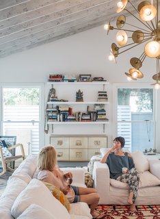 Actress Lena Headey (with her mother, Susan) worked with builder Ted Broden to give her 1950s house an open feel. The living room includes a Cloud Track Arm sofa and chair from Restoration Hardware, a Woven Accents rug, and a Keegan chandelier by Arteriors.