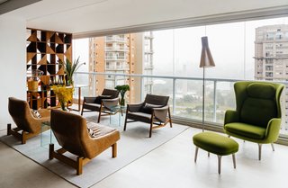 Overlooking a Niemeyer Masterpiece, This Flat is Filled with Brazilian Modern Gems - Photo 1 of 9 - In an apartment overlooking São Paulo’s Ibirapuera Park—completed in 1954 to commemorate the city’s 400th anniversary—the furniture is as distinctive as the view. Architect Flavio Castro of FCstudio worked closely with the residents to update and outfit the home, which is appointed with a mix of contemporary and Brazilian modern classics. A pair of Sérgio Rodrigues’s Paraty armchairs (in foreground)—designed for Brasilia’s Itamaraty Palace in 1963—face a duo of Jader Almeida’s Isa armchairs in the living area. The green Ro lounge and ottoman are by Jaime Hayon for Fritz Hansen.