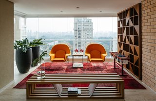 Overlooking a Niemeyer Masterpiece, This Flat is Filled with Brazilian Modern Gems - Photo 2 of 9 - Two Womb chairs by Eero Saarinen for Knoll and a Ring bench by Castro structure a reading area in the enclosed terrace.