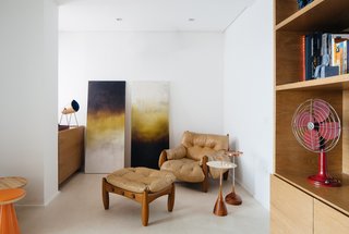 Overlooking a Niemeyer Masterpiece, This Flat is Filled with Brazilian Modern Gems - Photo 5 of 9 - An original 1961 Mole armchair and ottoman—an iconic Sérgio Rodrigues design made from oversize tufted leather cushions and rounded wood frames—sits in the office.