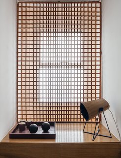 Overlooking a Niemeyer Masterpiece, This Flat is Filled with Brazilian Modern Gems - Photo 7 of 9 - FCstudio designed the gridded Muxarabi panel made of catuaba wood; placed in front of the home office window, it softens light to a diffuse glow.