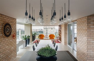 Overlooking a Niemeyer Masterpiece, This Flat is Filled with Brazilian Modern Gems - Photo 8 of 9 - On the terrace, a custom mixed-height table made from wood and granite encourages a communal cooking and dining experience. 