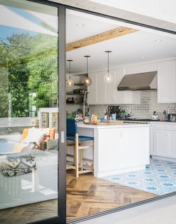 Fleetwood sliders open the kitchen and family room to the backyard. The pendants over the kitchen island are from Cisco Home; the bar chairs are by Studio One for Lost & Found.