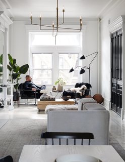 Jason lounges in one of two armchairs by midcentury designer Milo Baughman in the parlor-floor living room. The wood block coffee table is by Eric Slayton, a friend of the couple, and the modular Carmo sofa is from BoConcept. The Octahedron Side Table is by Eric Trine. A 1952 piece by French industrial designer Serge Mouille, the Three-Arm Floor Lamp—widely referred to as the "Praying Mantis," for its looming trio of arms—is a nod to the couple’s love of Parisian interiors; a branch-like chandelier by Los Angeles–based artist Gary ChapmanGary Chapman hangs overhead.