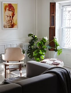 A Prostoria Match sofa from Cite pairs with a vintage armchair and a Ryan McGinley print in the family room on the garden floor.