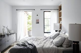 Antique Art Deco–style lamps flank a West Elm bed in the master bedroom, which accesses a private backyard garden. The smoke-colored Series 11 6 Drawer Console is from Blu Dot; the built-in shelving was custom-made by Wood Management.