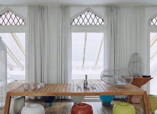 At designer and interior architect Danny Venlet’s home and atelier in Brussels, arched transom windows original to the structure harken back to its history as one of the city’s several béguinages—enclosed communities founded by a semi-monastic Christian order and built in a traditional Flemish style. Venlet enlarged the glass panes beneath, which overlook the courtyard. In bold juxtaposition to the architecture, his own product and furniture designs, including his 2007 Cage Aux Folles stainless-steel wire baskets, often reference industrial materials and aviation-inspired forms.