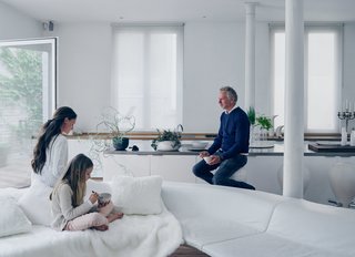 A palette of white-on-white textures and materials defines the living room. Venlet is joined by Lippens and their daughter, Nylah-Noy, on the Bendy Bay sectional—a modular, undulating fiberglass frame topped with leather cushions that he produced for Viteo in 2007. Cast-iron columns original to the structure, lacquered IKEA cabinets, and a custom stainless-steel countertop lined with a variant of Venlet’s Burdekin barstools make up the galley-style kitchen.