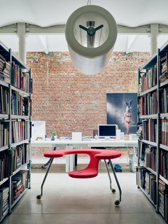 Recalling the form of an airplane engine, his cylindrical D2V2 pendant hovers above his sculptural Easy Rider, a mobile desk-seat hybrid set on castors.