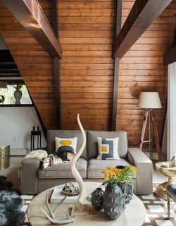 Focus on Furniture - Photo 2 of 3 - Original tongue-and-groove pine boards, restained a warm chestnut hue, run horizontally to the ceiling. The residents layered gray sheepskin rugs on top of wool berber carpeting, installed by Joseph Velletri’s Sons. 