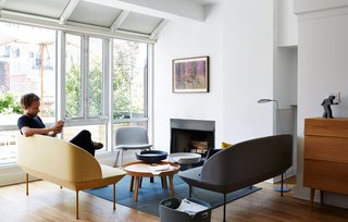 The setup around the fireplace includes a sister piece in a neutral gray, coffee tables by Thomas Bentzen, and a Visu lounge chair by Mika Tolvanen, all for Muuto.