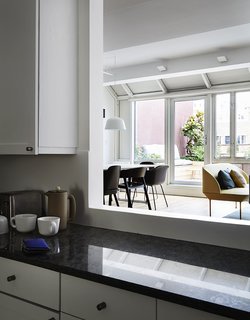 An opening in the kitchen wall allows a view of the terrace from behind the black marble counter.