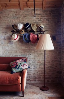 In a cozy nook the family calls the "snug," hats hang from a Thonet rack above a Noelle sofa by Pinch, which is upholstered in orange velvet by Kravet.