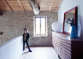 Floris, seven, stands on the mezzanine next to a walnut version of the Wave sideboard her father designed for Content by Terence Conran. The enamel water jug was found at a local brocante market.