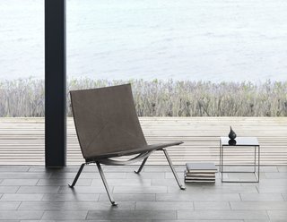 10 Things You Didn't Know About Poul Kjærholm - Photo 5 of 10 - As an evolution from the PK25, the PK22 is less sculptural and more refined. The chair made its first appearance in 1956. Instead of being made from one piece of steel, the construction allows the chair to be broken down, which makes it easier to ship. In considering that every aspect of the design counted, even the screws have aesthetic appeal. For the anniversary, the steel frame is darkened and finished in a nubuck leather. 