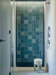 Tucked in a corner of the master bedroom, a curbless shower with Cea fixtures showcases a wall of patterned Italian tiles that coordinate with those used on the range hood in the kitchen.The designers sought to imbue the apartment’s minimalist framework with a handcrafted touch. "We wanted to add natural and warm elements to the palette," Di Stefano says. 