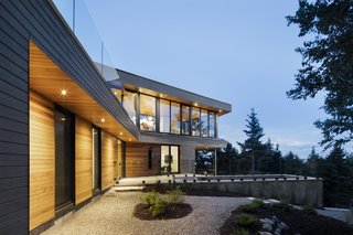 A Home Inspired by the Stars Soars Off the Ground - Photo 1 of 5 - The house is finished in a gray wood facade while the roof or most private areas of the home are covered in western cedar. The cedar extends into the interior for continuity. 