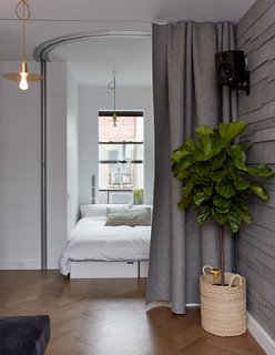 When friends visit, the office is flipped into a sleeping space and sealed by a curved Hufcor accordion door. Seating cubes by LifeEdited can be rearranged to form a full- or queen-size bed. An Edyn garden sensor monitors the fig tree; the wall-mounted speaker is by Kanto.