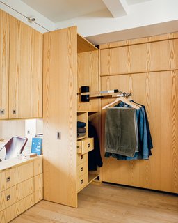 Stowing the queen-size Room Makers Murphy bed by SICO frees up access to custom built-in cabinets and pull-down closet rods by Hafele that illuminate when the door is opened. 