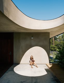 For the breezeway, Schwartz used concrete to achieve the feel of a hardscape courtyard. Uma basks beneath the egg-shaped opening. Schwartz opted for durable, easy-to-maintain materials—metal, concrete, and smooth integral stucco—that fare well in both extreme cold and heat.