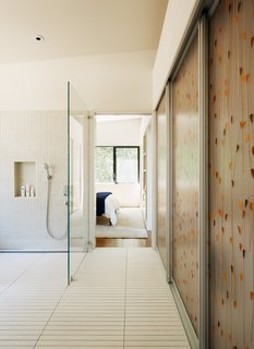In the bathroom, narrow porcelain floor tiles, which require more grout, provide extra traction to prevent slips. Schwartz chose Hansgrohe’s PuraVida shower mixer for its easy grip. Inlaid with a leaf pattern, lightweight and impact-resistant Varia Ecoresin sliding panels by 3form access the washer and dryer. 