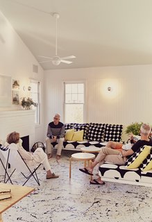 Damaged by Superstorm Sandy, a Fire Island Cottage is Rebuilt - Photo 2 of 6 - Residents Ann and Tony Spagnola sit with their architects, Peter Stamberg and Paul Aferiat, in front of the whitewashed brick fireplace in the living room. A vintage Butterfly chair joins custom sofas designed by the architects. Coffee tables by Alvar Aalto for Artek and pillows by Marimekko create a clean, Finnish-inflected environment.