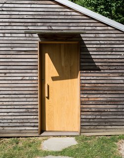 Cottage Industrious - Photo 2 of 10 - Taking a cue from a nearby farm structure, the couple used thin strips of larch to disguise imperfections in the original concrete block structure.