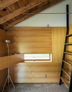 Cottage Industrious - Photo 5 of 10 - A custom ladder made of bent steel with oak treads leads to the sleeping loft, while a white oak panel swings opens to reveal an inset window. Longtime collaborator Jeffrey Kramer crafted the home’s wood elements. 