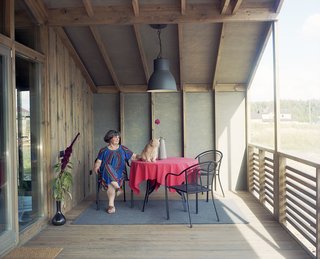 Anna’s house is a version of the DublDom 2.87, which has a starting price of 2.87 million rubles (about $46,000). The structure features a porch at each end lined in stained plywood. Anna surveys the countryside from under the gabled roof.